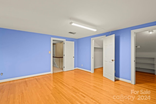 unfurnished bedroom with light hardwood / wood-style flooring, a closet, and a spacious closet