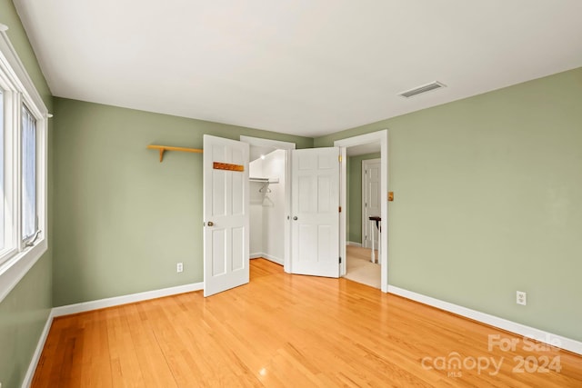 unfurnished bedroom with light hardwood / wood-style flooring and a walk in closet