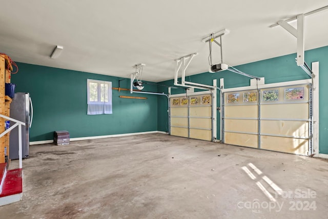 garage with a garage door opener and stainless steel fridge