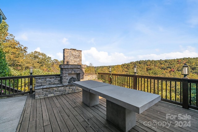 wooden terrace with an outdoor stone fireplace