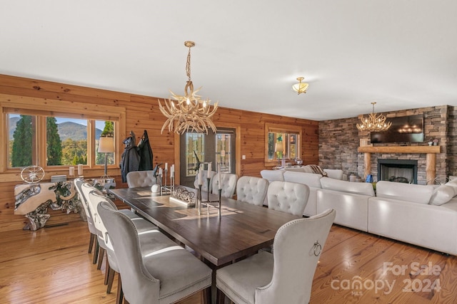 dining space with wooden walls, a fireplace, and light hardwood / wood-style floors