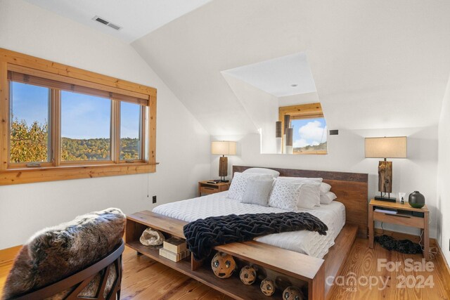 bedroom with lofted ceiling and light wood-type flooring