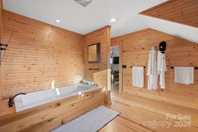 bathroom with hardwood / wood-style floors, wooden walls, and a tub