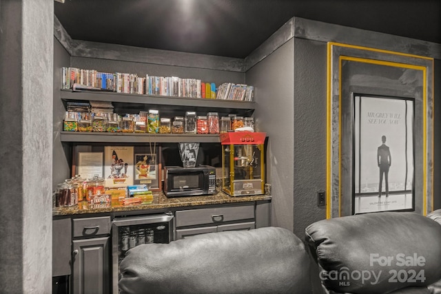 bar with beverage cooler and dark stone counters