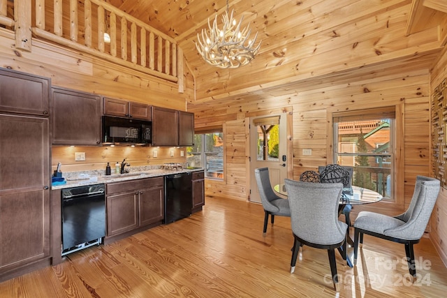 kitchen with high vaulted ceiling, wood walls, black appliances, light hardwood / wood-style floors, and decorative light fixtures