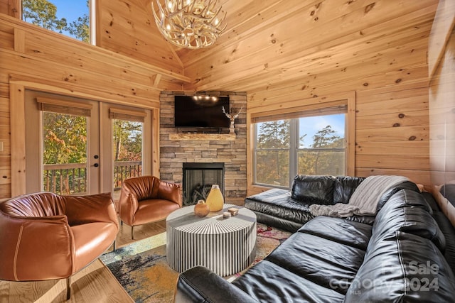 living room with a stone fireplace, wood walls, hardwood / wood-style flooring, and a high ceiling