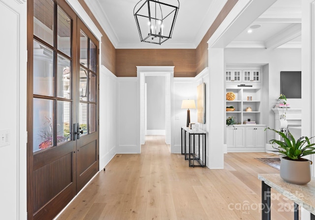 foyer entrance with crown molding, beamed ceiling, a notable chandelier, and light wood-type flooring