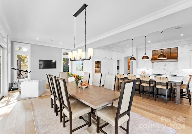 dining space with crown molding, light hardwood / wood-style flooring, and a chandelier