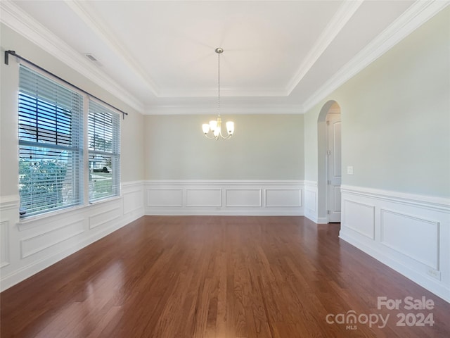 unfurnished dining area with dark wood-type flooring, crown molding, a raised ceiling, and a chandelier