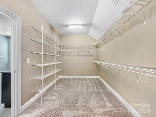 walk in closet with vaulted ceiling and carpet floors