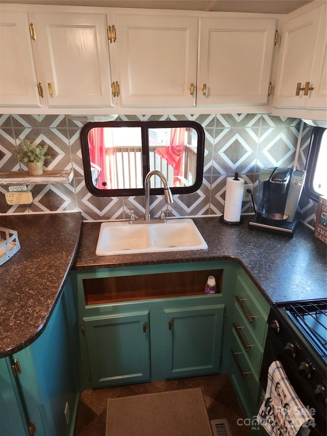 kitchen with black range oven, sink, white cabinets, and tasteful backsplash