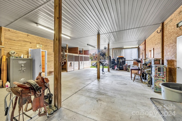 exterior space featuring a garage, wood walls, and concrete flooring