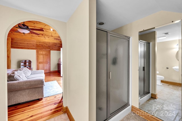 bathroom with a shower with door, vaulted ceiling, ceiling fan, toilet, and wood-type flooring