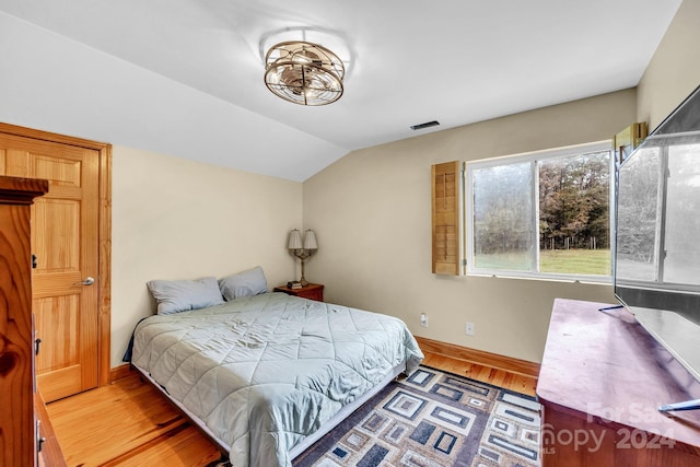 bedroom with hardwood / wood-style floors and lofted ceiling