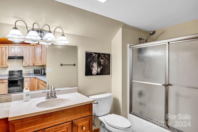 full bathroom featuring combined bath / shower with glass door, vanity, and toilet