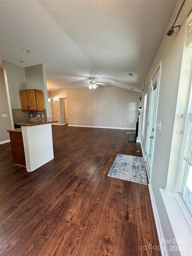 kitchen with sink, backsplash, a textured ceiling, ceiling fan, and dark wood-type flooring