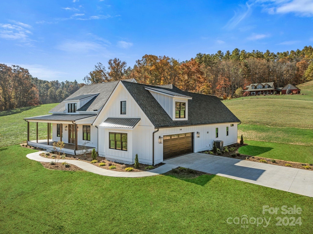 modern inspired farmhouse featuring covered porch, a garage, central AC unit, and a front lawn