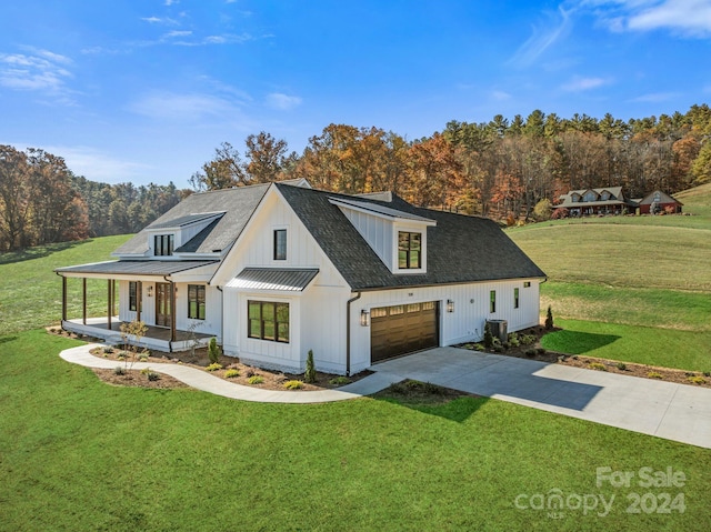 modern inspired farmhouse featuring covered porch, a garage, central AC unit, and a front lawn