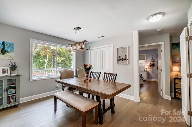 dining space featuring wood-type flooring and an inviting chandelier