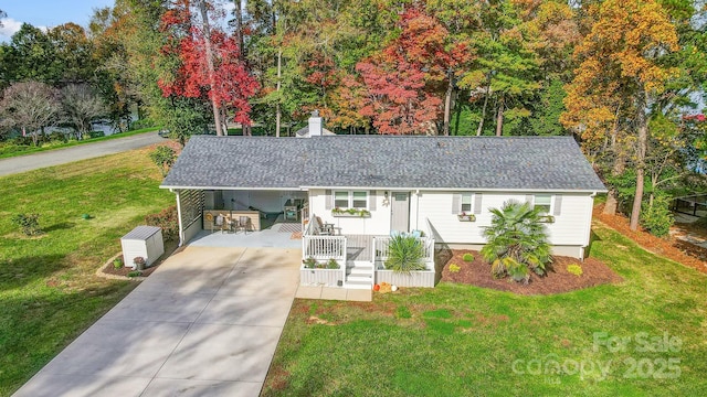 single story home featuring a shingled roof, an attached carport, concrete driveway, and a front yard