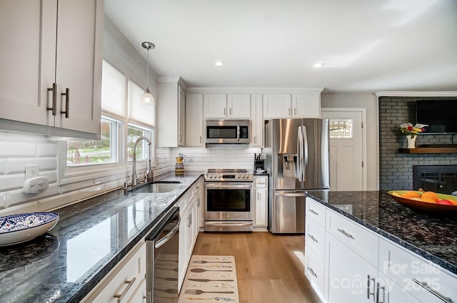 kitchen with a sink, appliances with stainless steel finishes, light wood finished floors, and a healthy amount of sunlight