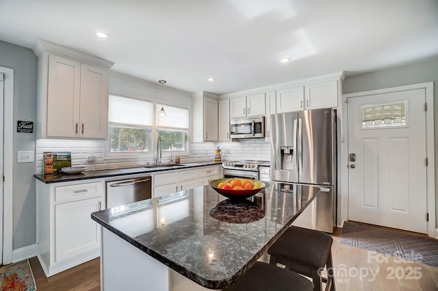 kitchen with backsplash, white cabinetry, stainless steel appliances, and a sink