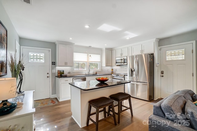 kitchen with tasteful backsplash, light wood-type flooring, a breakfast bar, appliances with stainless steel finishes, and a sink