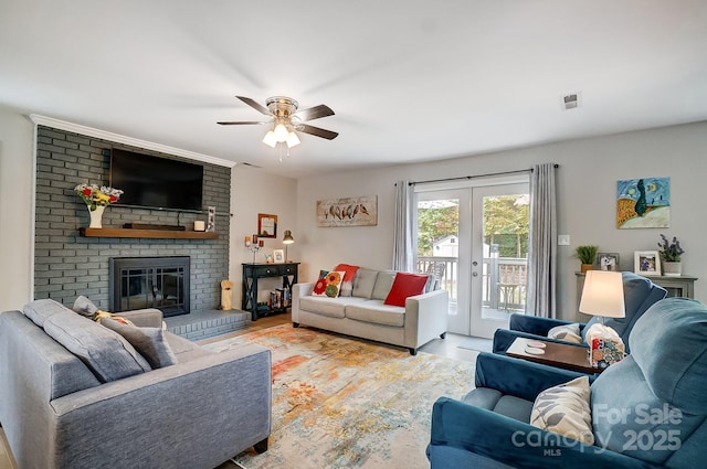 living room featuring ceiling fan, visible vents, wood finished floors, a brick fireplace, and french doors