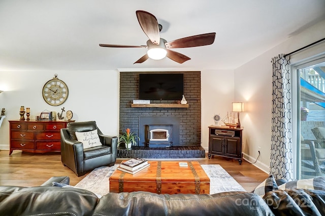living area featuring a fireplace, baseboards, a ceiling fan, and wood finished floors