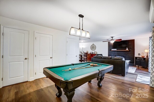 rec room featuring a brick fireplace, wood finished floors, pool table, and a ceiling fan
