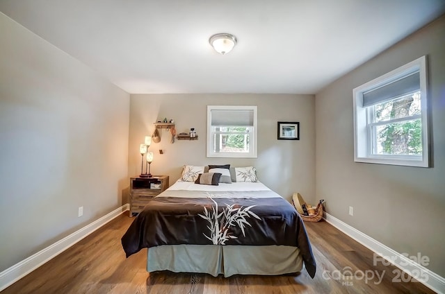 bedroom with multiple windows, baseboards, and wood finished floors