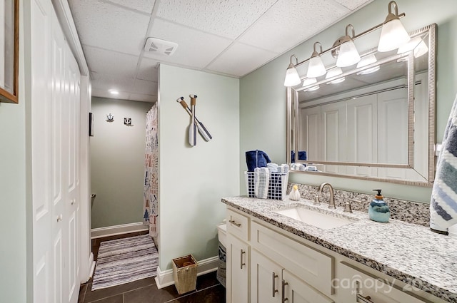 bathroom with tile patterned floors, a drop ceiling, visible vents, vanity, and baseboards