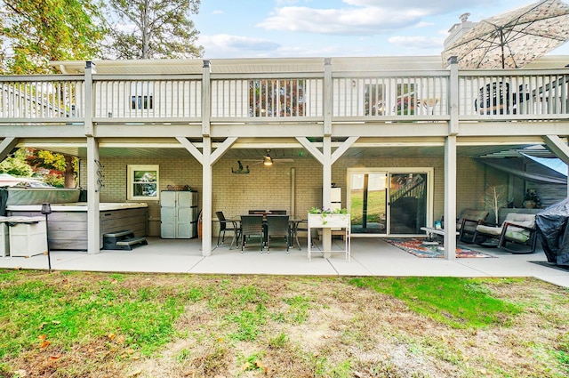 back of property with a patio area, brick siding, and a hot tub