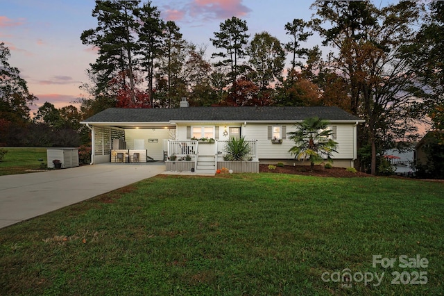 ranch-style home with driveway, a yard, a shingled roof, and an attached carport