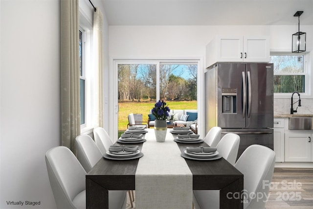 dining area with sink, wood-type flooring, and a healthy amount of sunlight