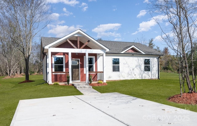 view of front facade featuring a front yard, covered porch, and roof with shingles