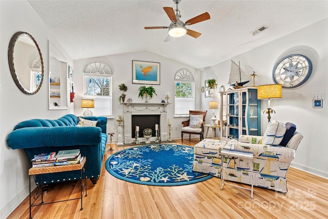 living room with a textured ceiling, a wealth of natural light, lofted ceiling, and hardwood / wood-style flooring