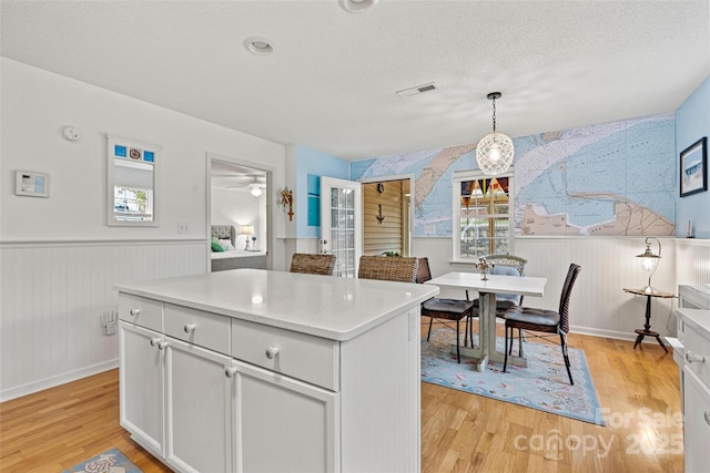 kitchen with ceiling fan, a center island, light hardwood / wood-style flooring, pendant lighting, and a textured ceiling