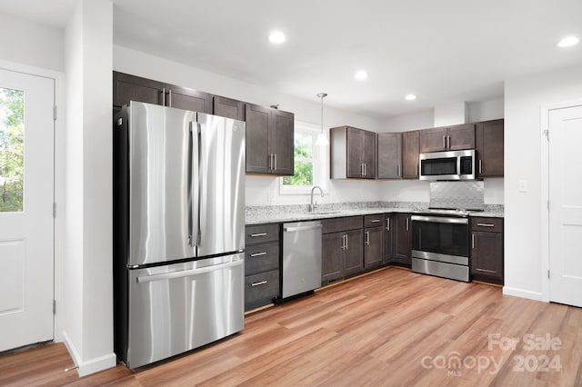 kitchen featuring pendant lighting, dark brown cabinets, backsplash, and stainless steel appliances