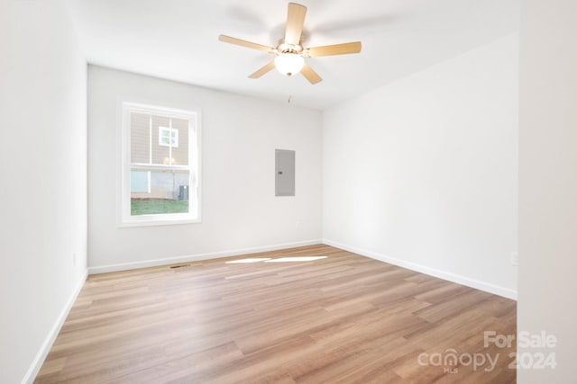 spare room featuring ceiling fan, electric panel, and light hardwood / wood-style flooring