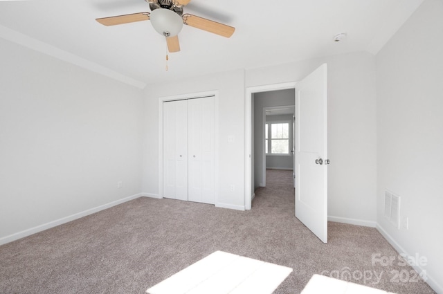 unfurnished bedroom with ceiling fan, light colored carpet, and a closet