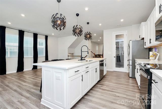 kitchen featuring pendant lighting, white cabinets, an island with sink, and stainless steel appliances