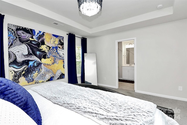 bedroom featuring ensuite bath, a raised ceiling, and carpet floors