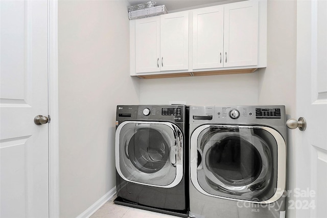 washroom with cabinets, washing machine and dryer, and light tile patterned floors