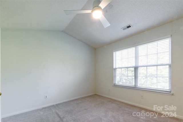 empty room with lofted ceiling, a textured ceiling, light colored carpet, and ceiling fan