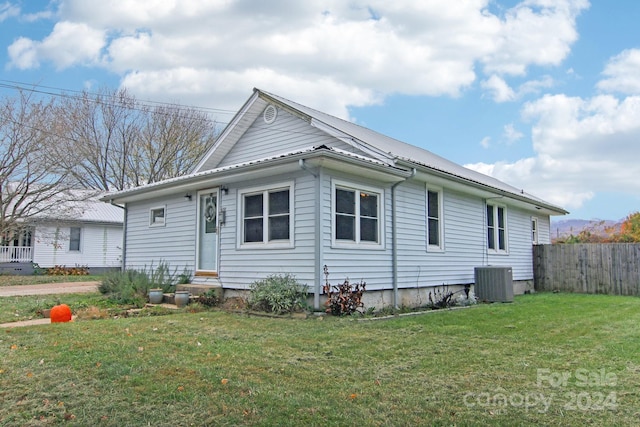 view of front of house with central AC unit and a front lawn