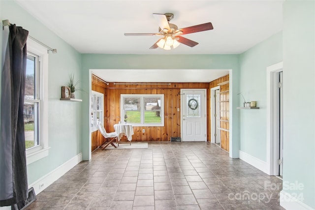 tiled entryway with ceiling fan and wooden walls