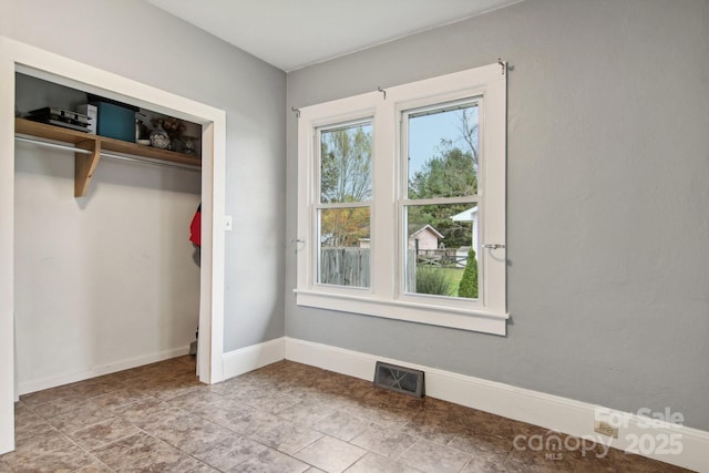 unfurnished bedroom featuring multiple windows and a closet