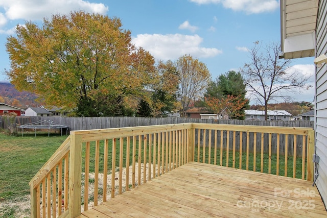 wooden deck featuring a trampoline and a yard