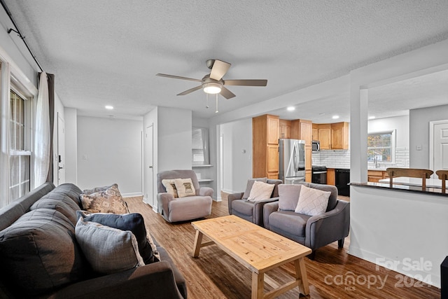 living room featuring ceiling fan, wood-type flooring, and a textured ceiling